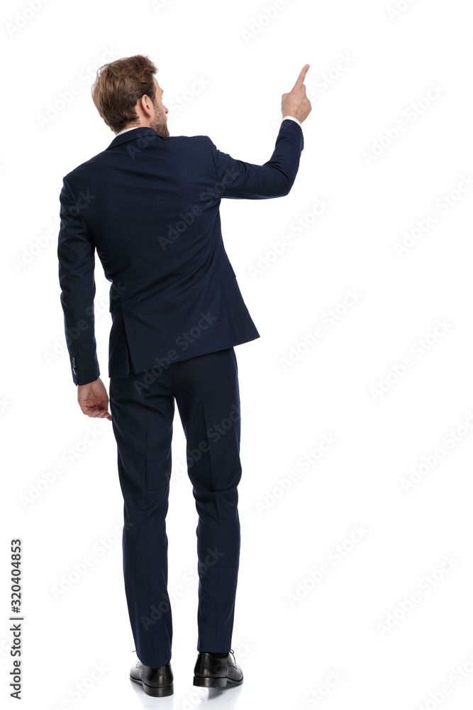 young businessman in navy blue suit pointing finger to side young businessman in navy blue suit pointing finger to side