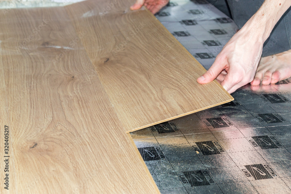 Laying laminate flooring. Close-up on male hand with floor panel. Laying laminate flooring. Close-up on male hand with floor panel.