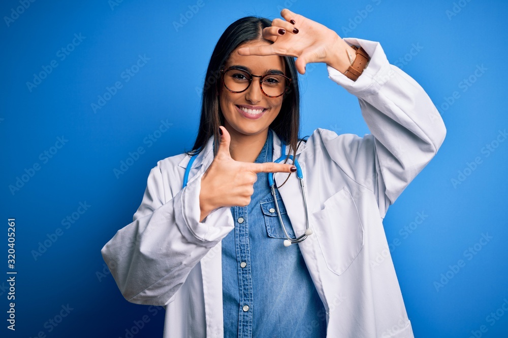Young beautiful doctor woman wearing stethoscope and glasses over blue background smiling making frame with hands and fingers with happy face. Creativity and photography concept. Young beautiful doctor woman wearing stethoscope and glasses over blue background smiling making frame with hands and fingers with happy face. Creativity and photography concept.