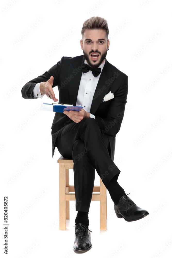 businessman sitting and pointing to clipboard upset businessman sitting and pointing to clipboard upset