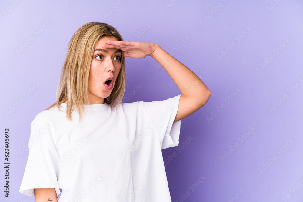 Young blonde caucasian woman isolated looking far away keeping hand on forehead. Young blonde caucasian woman isolated looking far away keeping hand on forehead.