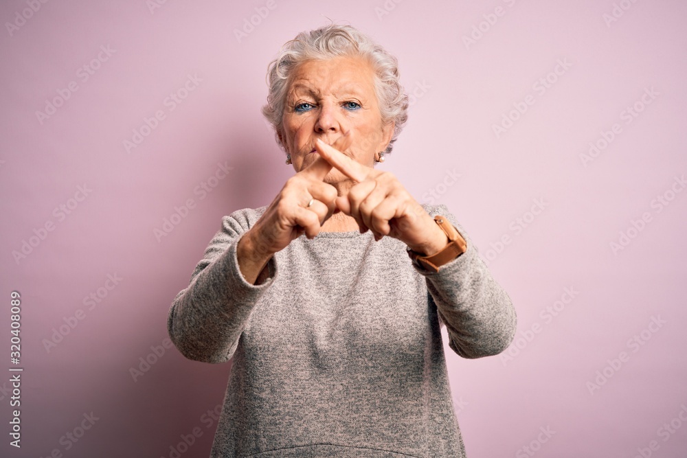 Senior beautiful woman wearing casual t-shirt standing over isolated pink background Rejection expression crossing fingers doing negative sign Senior beautiful woman wearing casual t-shirt standing over isolated pink background Rejection expression crossing fingers doing negative sign