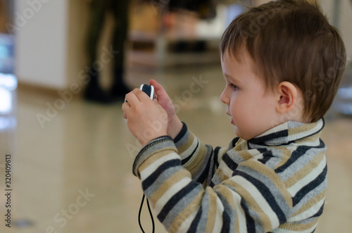 Boy taking a photo with a camera. The child is holding camera with both hands. Baby boy with camera