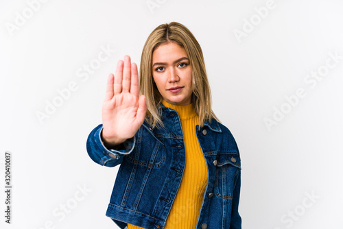 Young blonde caucasian woman isolated standing with outstretched hand showing stop sign, preventing you.
