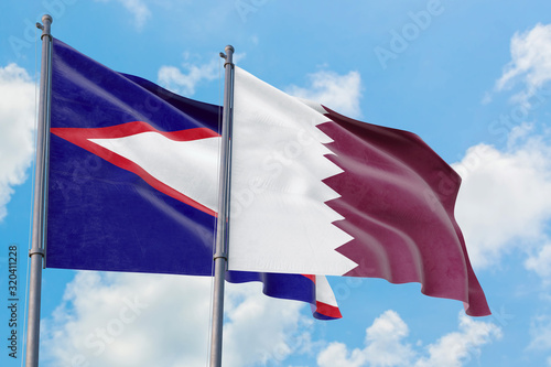 Qatar and American Samoa flags waving in the wind against white cloudy blue sky together. Diplomacy concept  international relations.