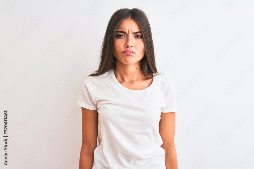 Young beautiful woman wearing casual t-shirt standing over isolated white background skeptic and nervous, frowning upset because of problem. Negative person. Young beautiful woman wearing casual t-shirt standing over isolated white background skeptic and nervous, frowning upset because of problem. Negative person.