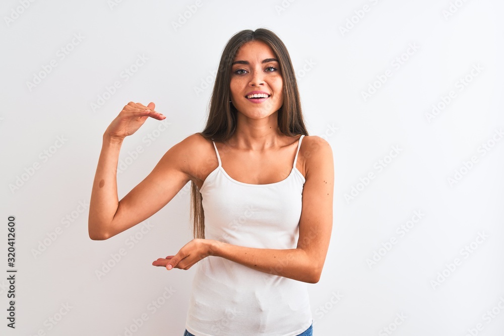 Young beautiful woman wearing casual t-shirt standing over isolated white background gesturing with hands showing big and large size sign, measure symbol. Smiling looking at the camera. Measuring Young beautiful woman wearing casual t-shirt standing over isolated white background gesturing with hands showing big and large size sign, measure symbol. Smiling looking at the camera. Measuring