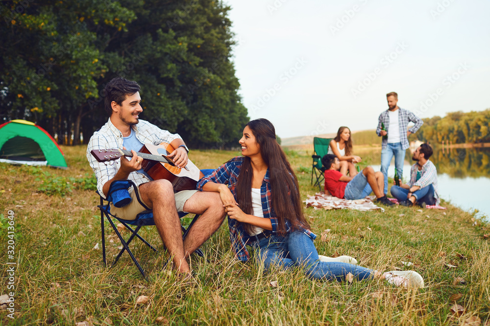 Friends with a guitar on a picnic on nature in autumn. Friends with a guitar on a picnic on nature in autumn.
