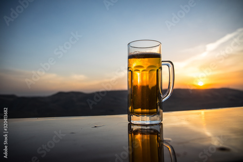 Valokuva Glass of beer on a beach at sunset