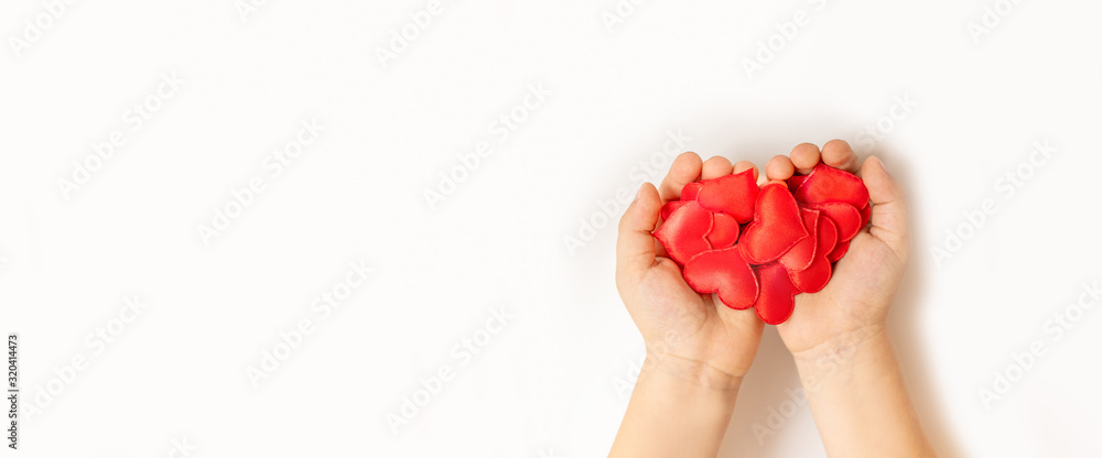 Close up of child hands holding red hearton white background Close up of child hands holding red hearton white background