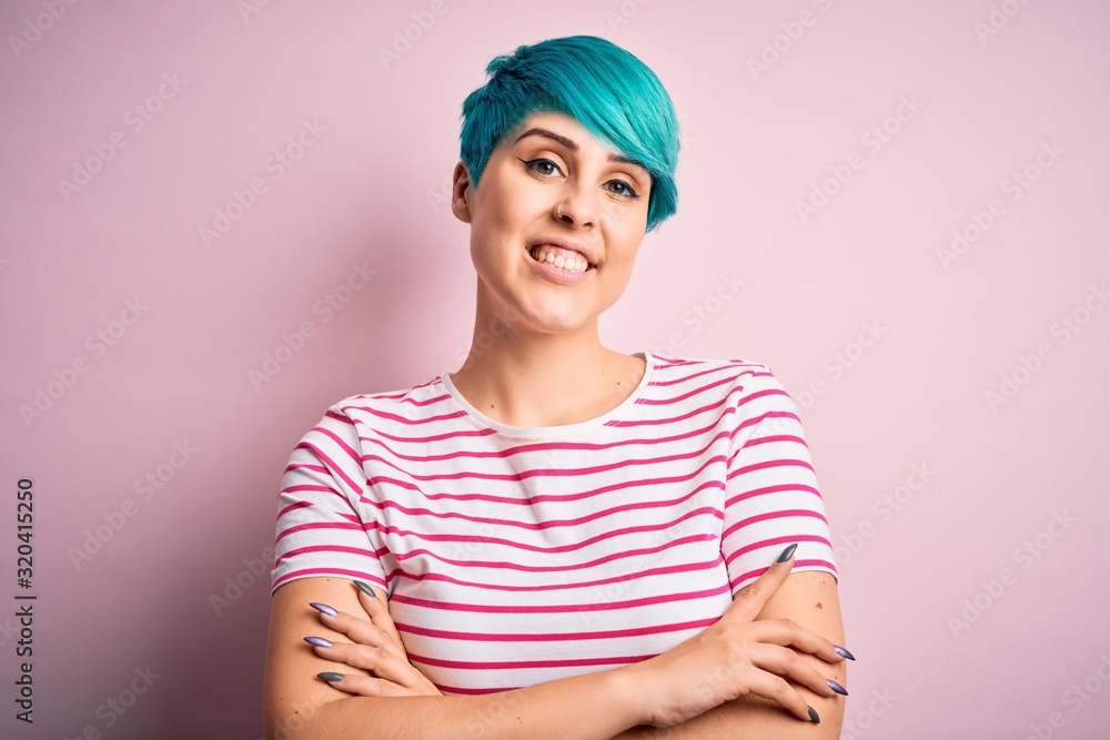 Young beautiful woman with blue fashion hair wearing casual striped t-shirt happy face smiling with crossed arms looking at the camera. Positive person. Young beautiful woman with blue fashion hair wearing casual striped t-shirt happy face smiling with crossed arms looking at the camera. Positive person.