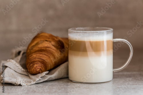 A cup of coffee latte macchiato with a croissant