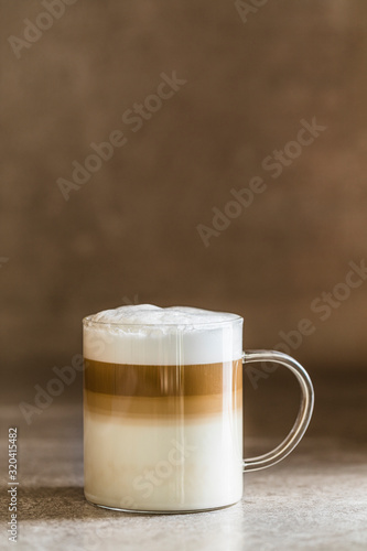 Bilde på lerret A glass of caffe latte macchiato coffee, vertical with brown background