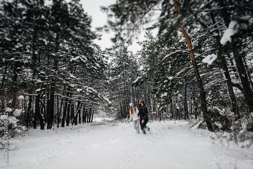 A couple embraces in a snowy forest against a background of trees