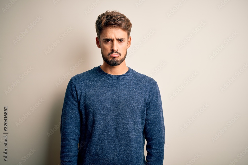 Young handsome man with beard wearing casual sweater standing over white background depressed and worry for distress, crying angry and afraid. Sad expression. Young handsome man with beard wearing casual sweater standing over white background depressed and worry for distress, crying angry and afraid. Sad expression.