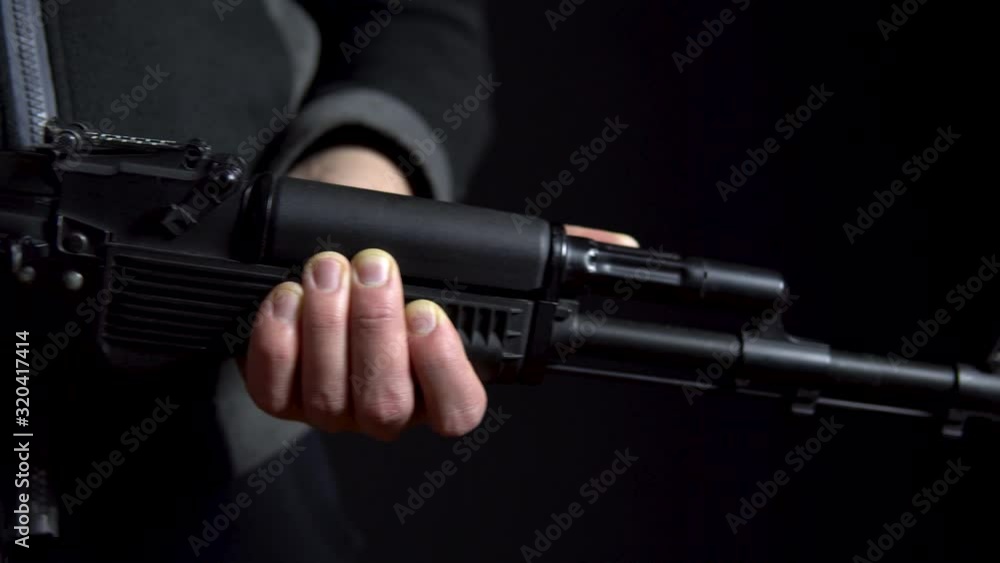 A bandit stands with a gun in hand on a black background. Close-up panorama from left to right. A bandit stands with a gun in hand on a black background. Close-up panorama from left to right.
