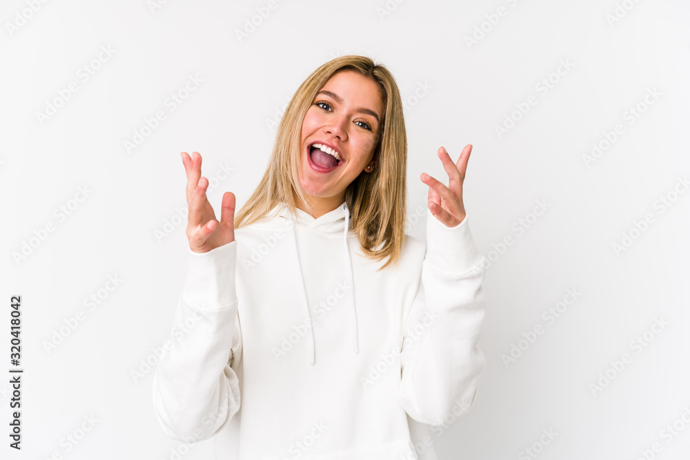 Young blonde caucasian woman isolated receiving a pleasant surprise, excited and raising hands. Young blonde caucasian woman isolated receiving a pleasant surprise, excited and raising hands.