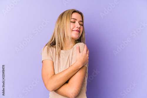 Young blonde caucasian woman isolated hugs, smiling carefree and happy.