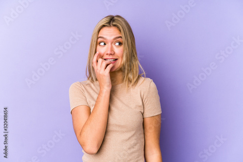 Young blonde caucasian woman isolated biting fingernails, nervous and very anxious.