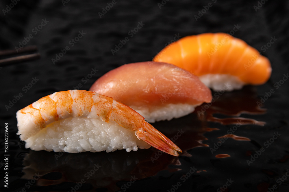 Nigiri sushi set with shrimp, salmon and tuna on black glossy plate, selected focus Nigiri sushi set with shrimp, salmon and tuna on black glossy plate, selected focus