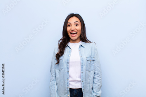 Schilderij op canvas young latin pretty woman looking happy and pleasantly surprised, excited with a