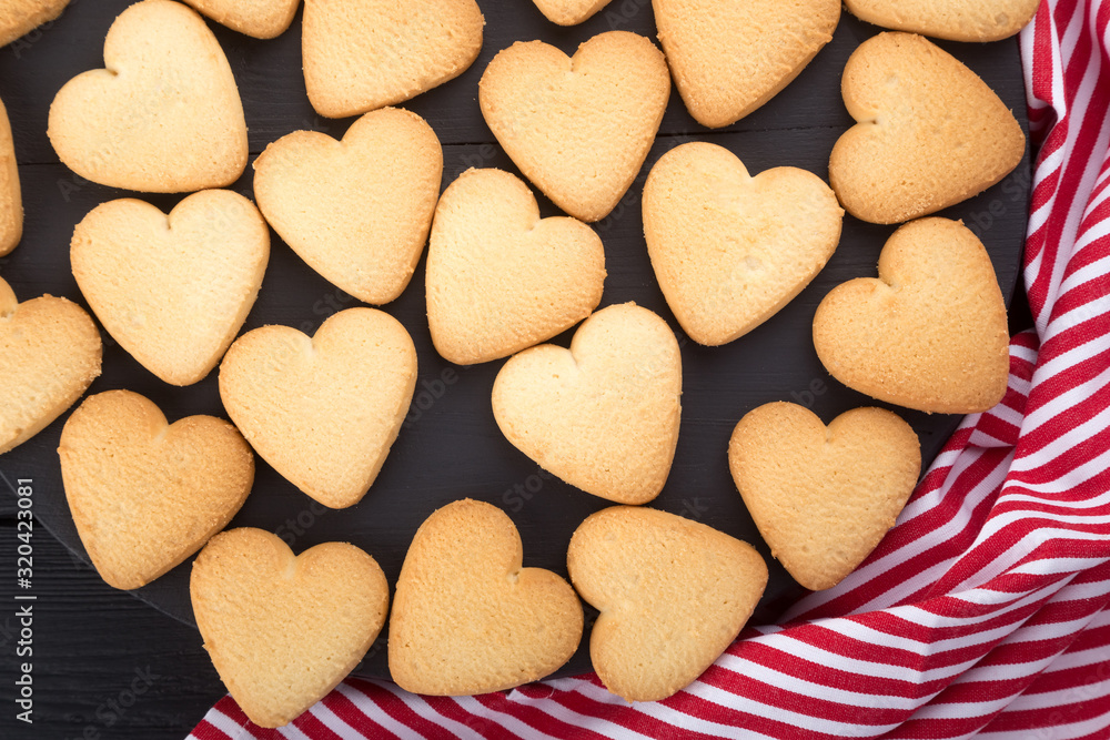 Heart shaped cookies decorated for Valentine's Day. Free space for text. Wooden plate with heart shaped cookies on a black wooden table Heart shaped cookies decorated for Valentine's Day. Free space for text. Wooden plate with heart shaped cookies on a black wooden table