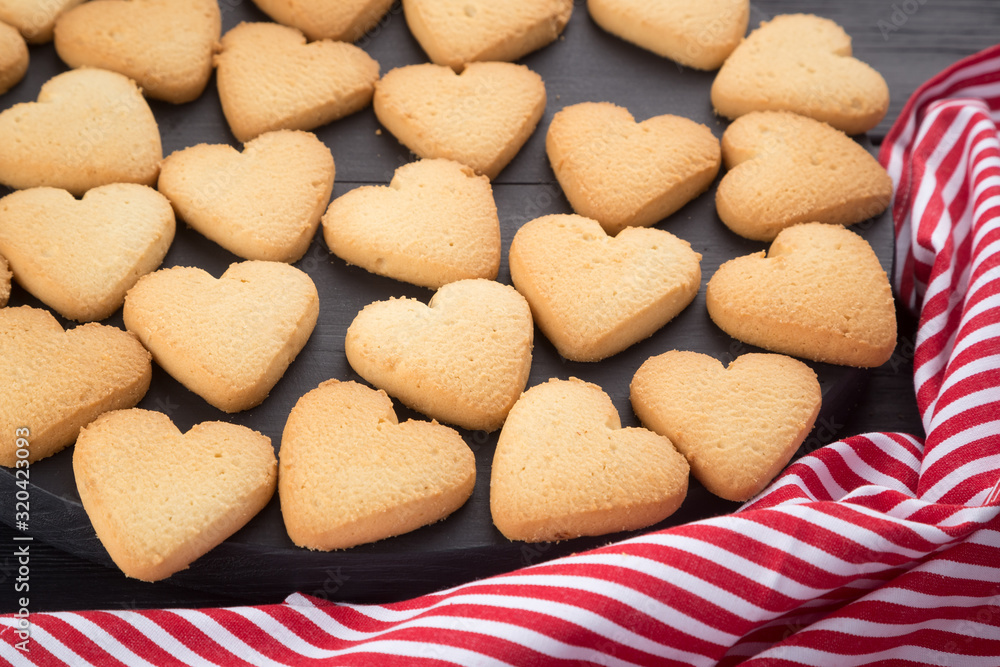 Heart shaped cookies decorated for Valentine's Day. Free space for text. Wooden plate with heart shaped cookies on a black wooden table Heart shaped cookies decorated for Valentine's Day. Free space for text. Wooden plate with heart shaped cookies on a black wooden table