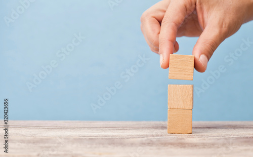 business man puts three wooden blocks on top of each other photo