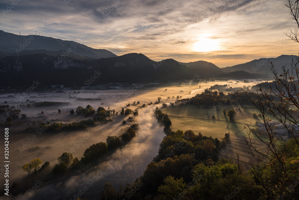 Abstract with Airuno on Adda river in Italy at sunrise with myst fog trees foliage in autumn fall season