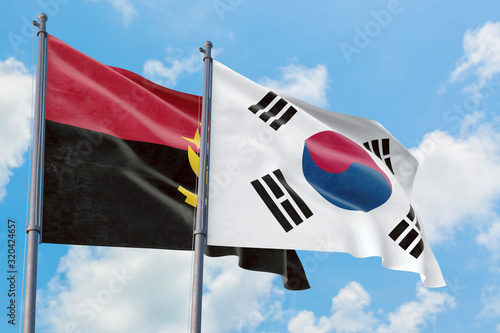 South Korea and Angola flags waving in the wind against white cloudy blue sky together. Diplomacy concept, international relations.
