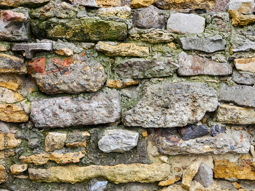 Old stone wall of colored stones close-up background texture