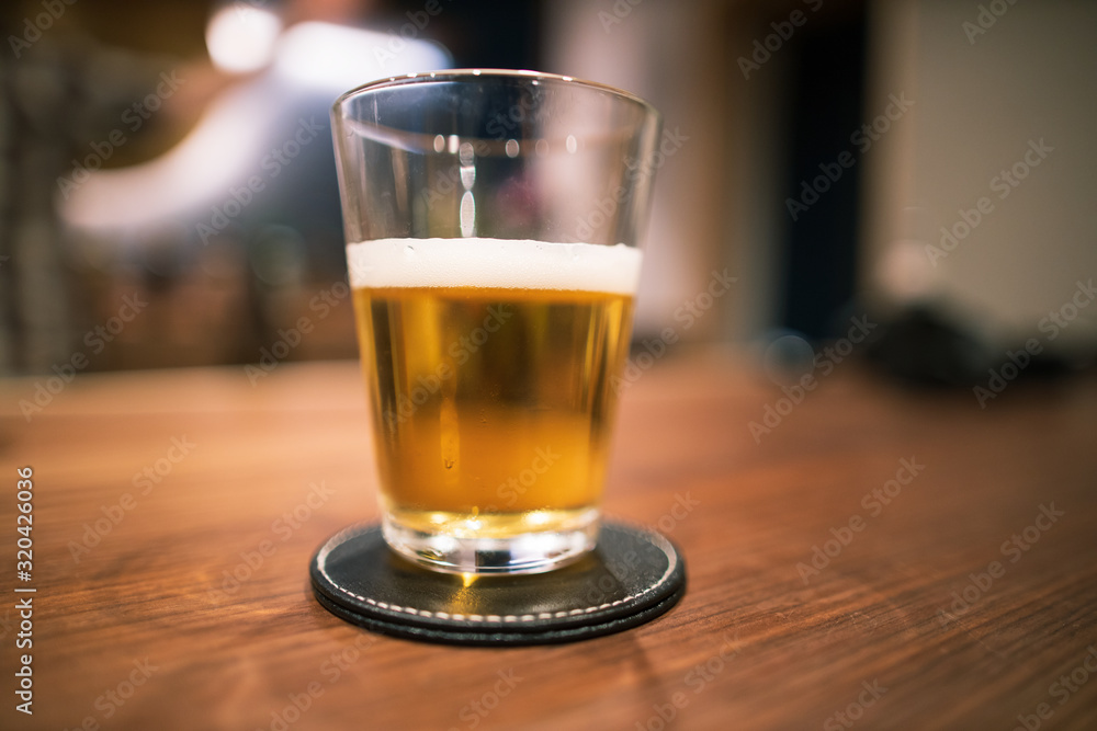 Half full pint of beer in glass on wooden bar Half full pint of beer in glass on wooden bar