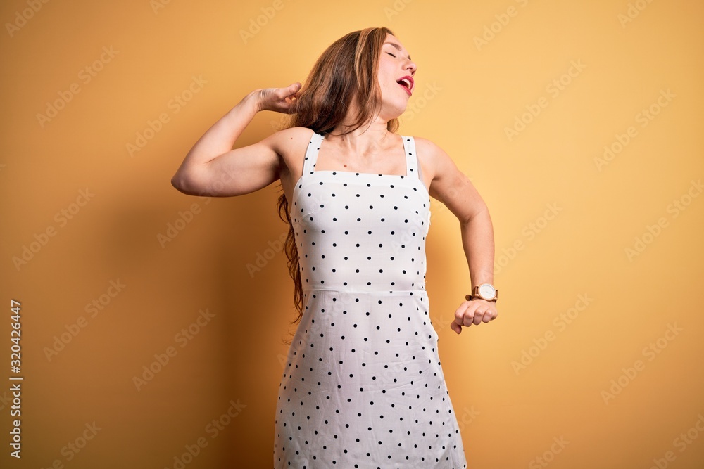 Young beautiful blonde woman on vacation wearing summer dress over yellow background stretching back, tired and relaxed, sleepy and yawning for early morning Young beautiful blonde woman on vacation wearing summer dress over yellow background stretching back, tired and relaxed, sleepy and yawning for early morning