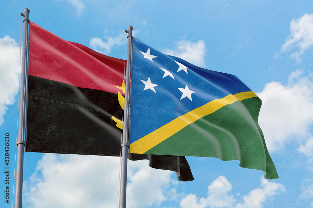 Solomon Islands and Angola flags waving in the wind against white cloudy blue sky together. Diplomacy concept, international relations. Solomon Islands and Angola flags waving in the wind against white cloudy blue sky together. Diplomacy concept, international relations.