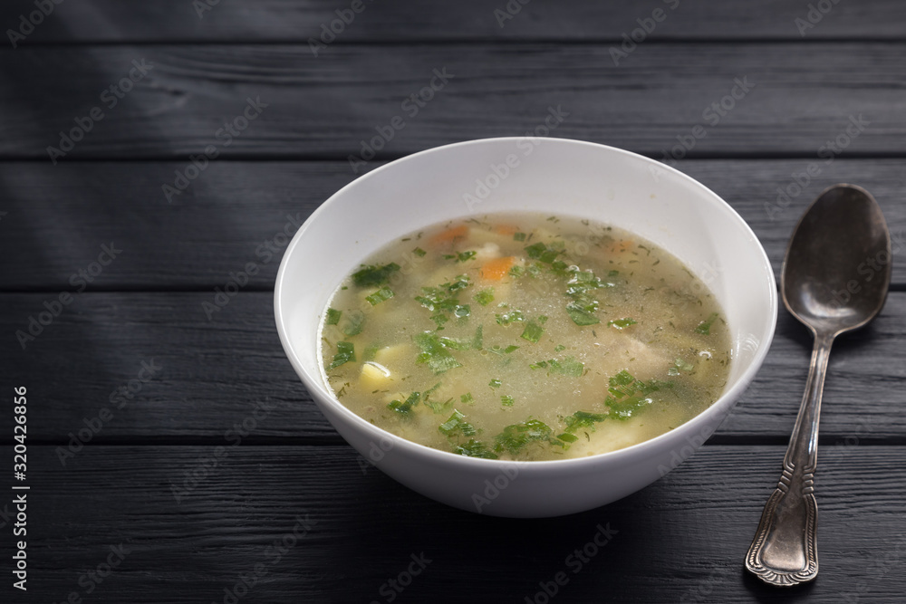 Bowl of chicken soup with bread. Chicken soup in a white plate on a black wooden table. Chicken noodle. bakso, meatball soup with noodles. Free space for text. Bowl of chicken soup with bread. Chicken soup in a white plate on a black wooden table. Chicken noodle. bakso, meatball soup with noodles. Free space for text.