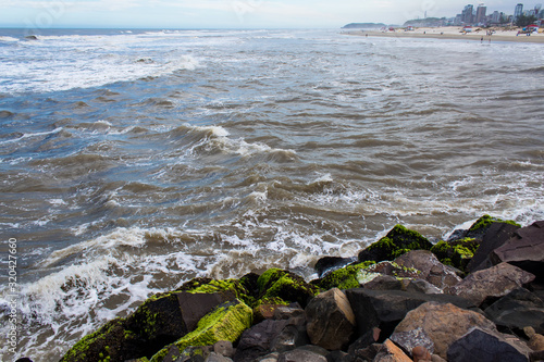 Ondas fortes na Praia dos Molhes da cidade de Torres, ao fundo a cidade abaixo de nuvens de chuva  photo