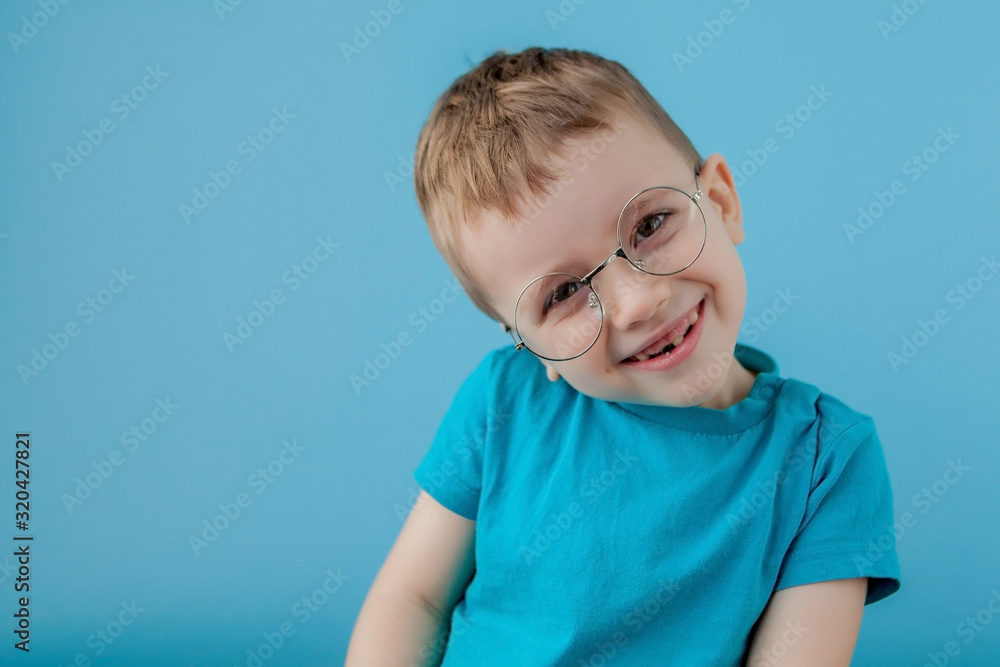 Portrait of a little smiling boy in a funny glasses. School. Preschool. Fashion. Studio portrait on a blue background, copy space - obrazy, fototapety, plakaty 