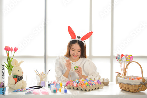 Easter, holiday concept - close up of young women coloring eggs for easter
