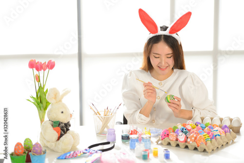 Easter, holiday concept - close up of young women coloring eggs for easter