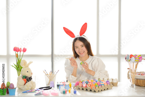 Easter, holiday concept - close up of young women smiling and coloring eggs for easter