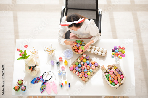 Easter, holiday concept - top view of young women coloring eggs for easter