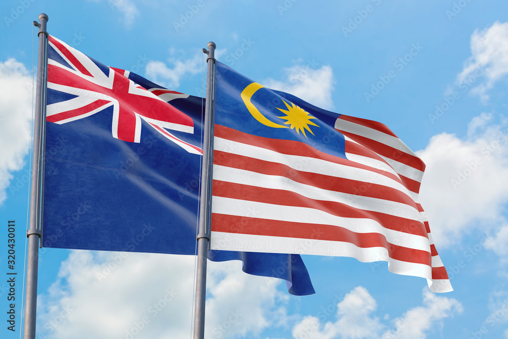 Malaysia and Anguilla flags waving in the wind against white cloudy blue sky together. Diplomacy concept, international relations.