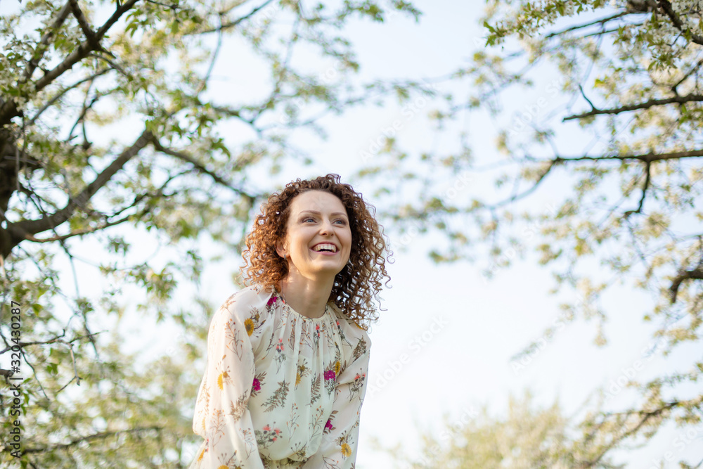 Young attractive girl walks in spring green park enjoying flowering nature Young attractive girl walks in spring green park enjoying flowering nature