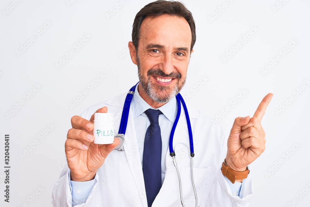 Middle age doctor man holding pills standing over isolated white background very happy pointing with hand and finger to the side Middle age doctor man holding pills standing over isolated white background very happy pointing with hand and finger to the side
