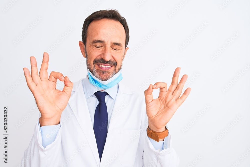 Middle age scientist man wearing coat and medical mask over isolated white background relax and smiling with eyes closed doing meditation gesture with fingers. Yoga concept. Middle age scientist man wearing coat and medical mask over isolated white background relax and smiling with eyes closed doing meditation gesture with fingers. Yoga concept.