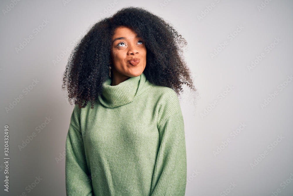 Young beautiful african american woman with afro hair wearing green winter sweater smiling looking to the side and staring away thinking. Young beautiful african american woman with afro hair wearing green winter sweater smiling looking to the side and staring away thinking.