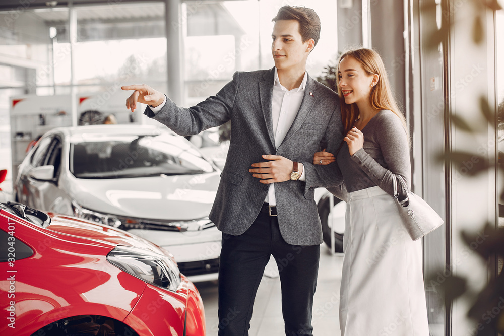 Couple buying the car. Pair in a car salon. Husband with vife choose the automobile Couple buying the car. Pair in a car salon. Husband with vife choose the automobile