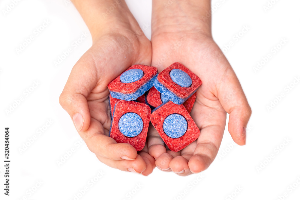 Hands holding many red and blue dishwasher soap tablets close up, white background Hands holding many red and blue dishwasher soap tablets close up, white background
