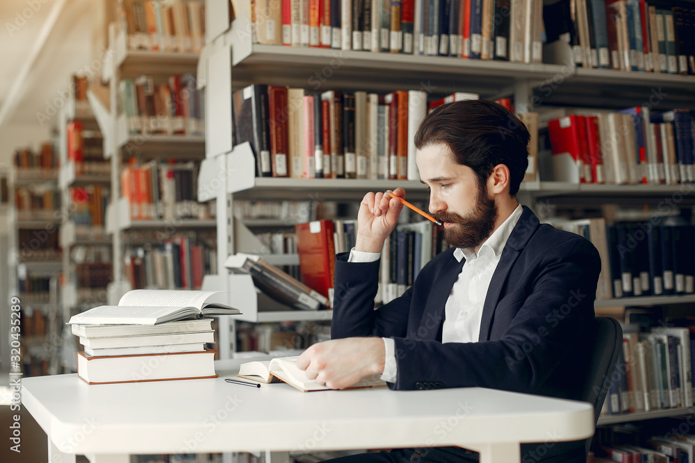 Man in a library. Guy in a black suit. Student with a books. Man in a library. Guy in a black suit. Student with a books.