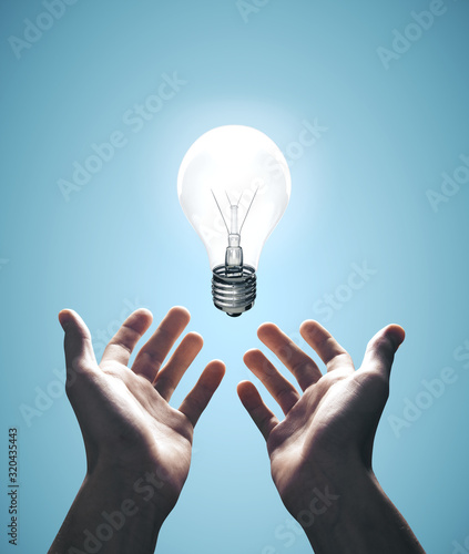 Hands holding bulb on blue background